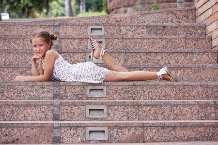 笑的小女孩躺在城市建筑的楼梯上图片