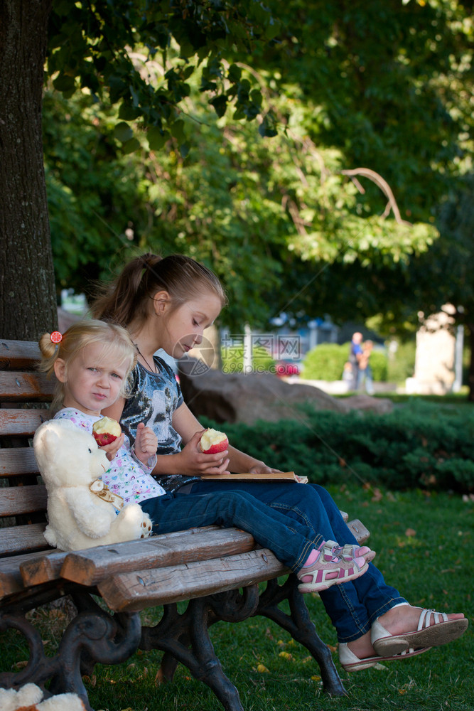 两个姐妹坐在公园的长凳上图片