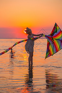 女孩日落时在海边放风筝图片