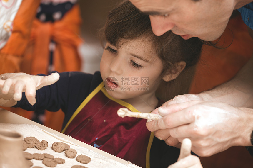 与他父亲一起做泥土雕塑的小女孩图片