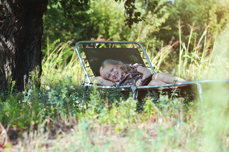 乡村暑假小笑的女孩躺在花园的椅子上图片