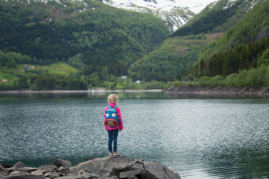 站在挪威湖岸边的金发小女孩图片