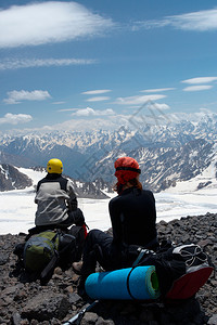 两名登山者坐在岩石上看着山地全景背景图片