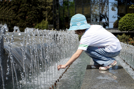 女孩在城市公园用喷泉水玩图片