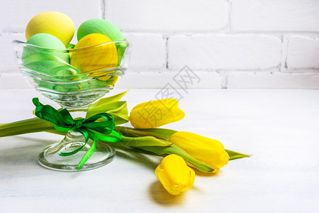 东面背景玻璃花瓶和郁金香里有绿色和黄的彩蛋快乐东面贺卡复制空间图片