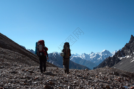 两个徒步旅行者上山蓝天空在背景中图片