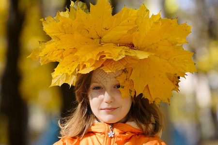 年轻女孩在公园用黄色的树叶图片