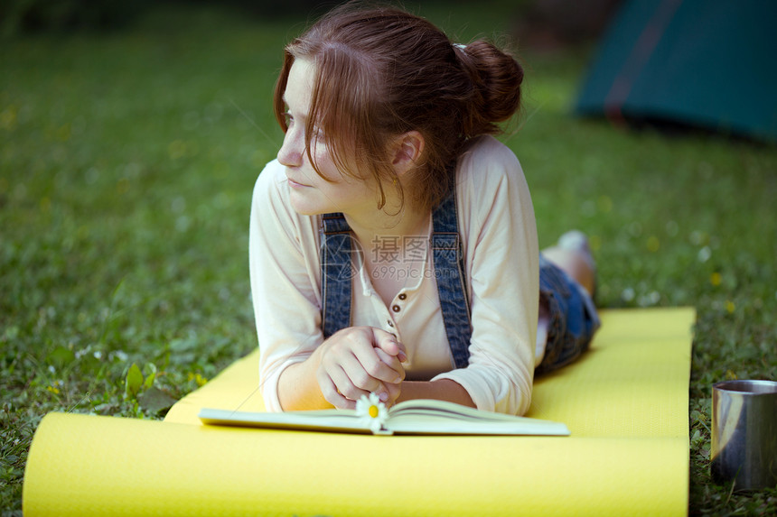 徒步旅行女青年在瑜伽垫上读书图片