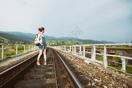 青年女孩背着包徒步旅行在铁路桥上图片