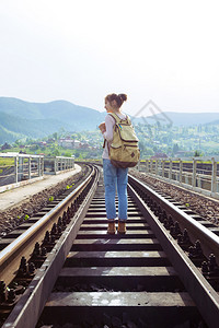 青年女孩背着包徒步旅行在铁路桥上图片