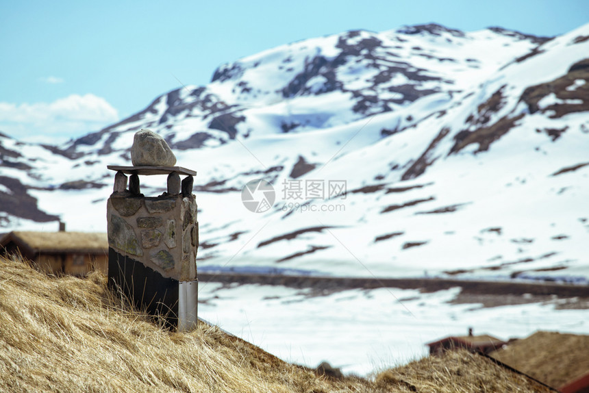 诺维坚传统房屋上的烟囱和山顶雪峰背景图片