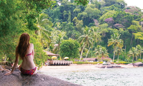 女孩坐在海滩石头上看着巴西图片