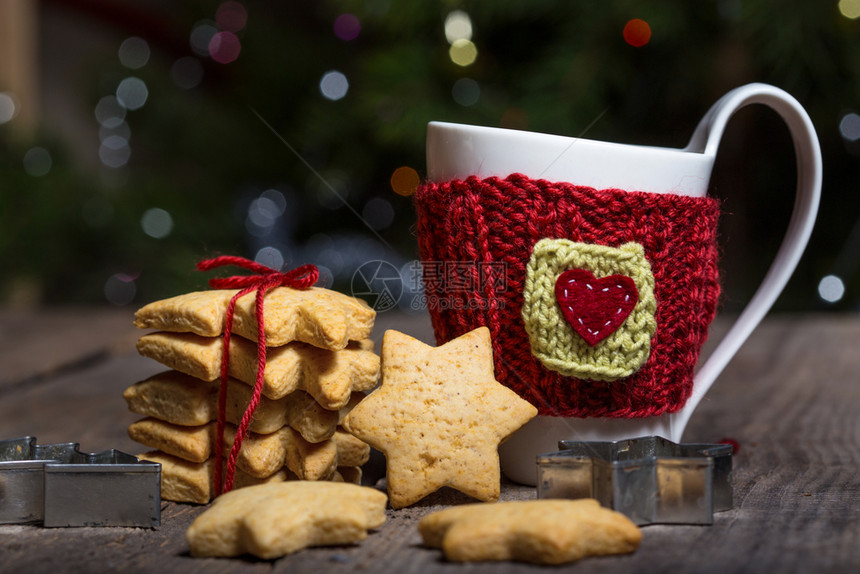圣诞节编织的羊毛杯和在木制桌上的星形姜饼图片