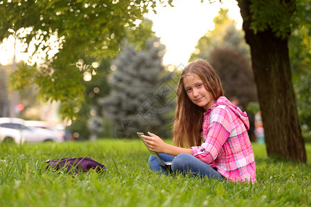 拿着笔记本的女孩坐在草地上图片