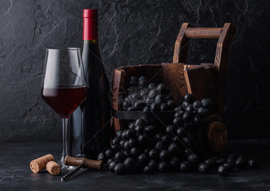 高雅的玻璃和一瓶红色葡萄酒有古老的木桶内深葡萄底黑色石块图片