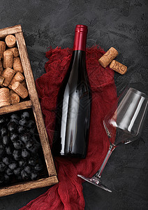在红布上装满白玻璃和黑葡萄的红酒瓶装箱内放在黑木本底的旧图片