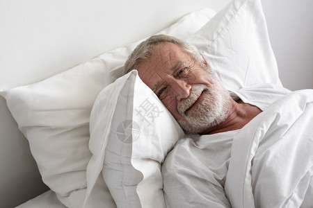 高年男子睡在房间里的床上时微笑地着睡觉图片