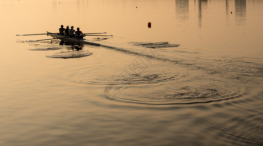 日出照亮了在伦敦码头练习独木舟的四名赛艇队员四人赛艇队练习赛独木舟背景图片