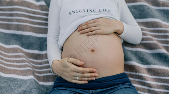 躺在毯子上的孕妇腹部特写背景图片