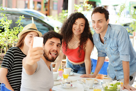 一群朋友在咖啡店的手机上自拍人们一起玩乐友谊的概念图片
