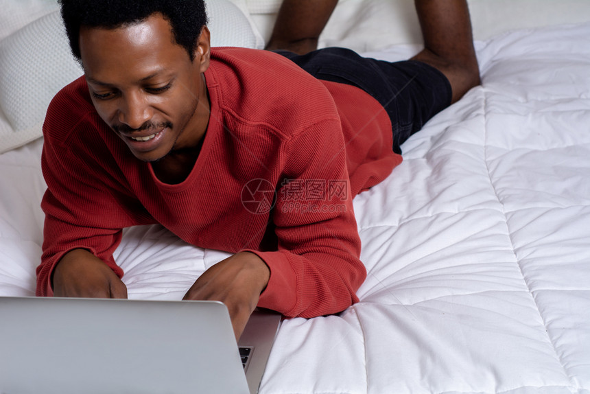 美国年轻人在床上用笔记本电脑图片