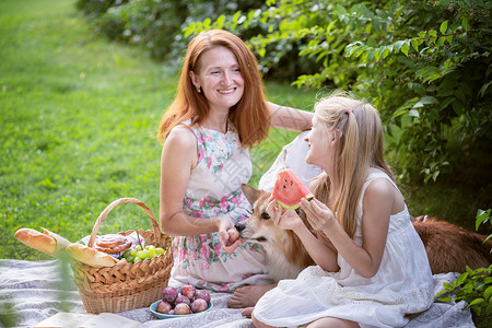 快乐的妈女儿和菜篮子在绿草上吃饭背景图片