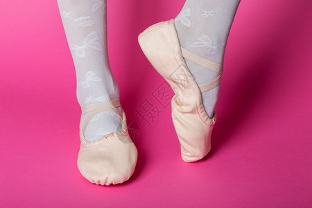 小芭蕾舞者在粉红色背景上用指尖向腿芭蕾舞姿势图片