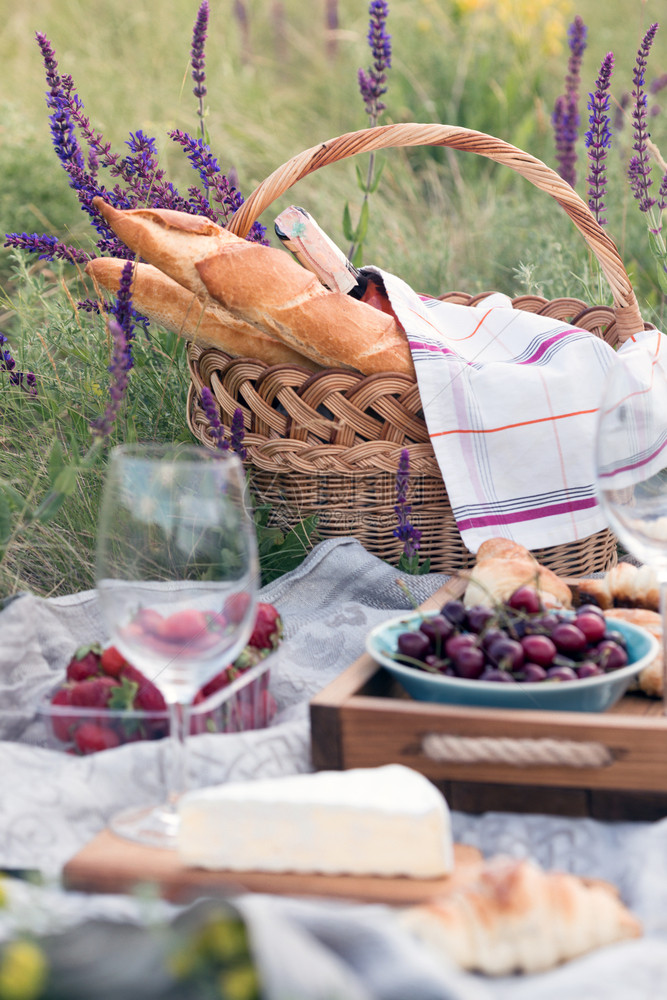 夏季在草地野餐奶酪饼面包草莓樱桃葡萄酒羊角面包和篮子图片