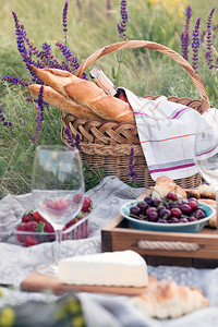 夏季在草地野餐奶酪饼面包草莓樱桃葡萄酒羊角面包和篮子图片
