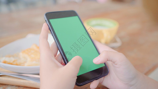 手机页面素材年轻女使用带绿色屏幕的黑手机设备年轻女在咖啡馆坐着时持有智能手机滚动页面铬密钥背景