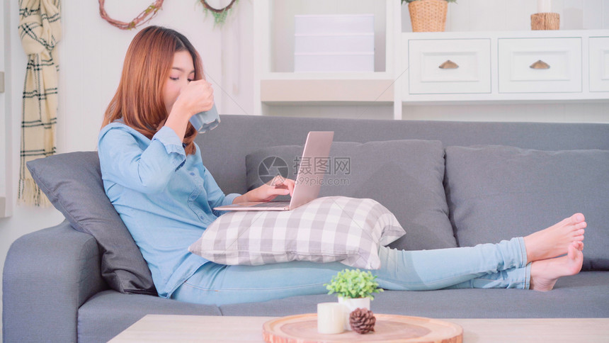穿着电脑或笔记本拿着一杯咖啡或茶躺在沙发上图片