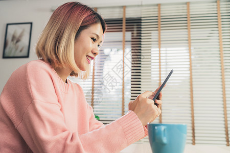 快乐的女使用电话在家中发短信阅读和购买图片