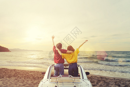 日落时在热带海滩的汽车里快乐年轻夫妇暑假旅行和期概念图片