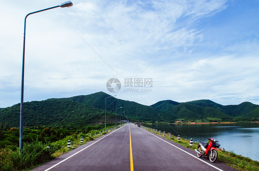 湖边街上老红色摩托车夏季天空和山丘背景图片