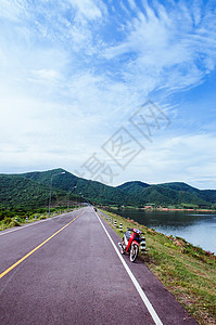 湖边街上老红色摩托车夏季天空和山丘背景高清图片