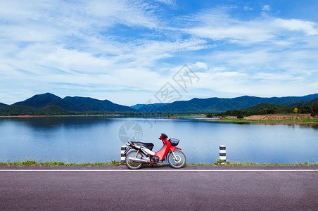 蓝色湖边的古红摩托车公园夏季天空和山丘背景高清图片