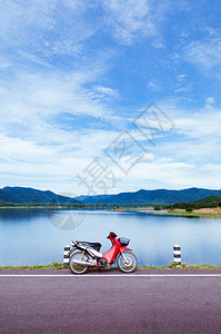 蓝色湖边的古红摩托车公园夏季天空和山丘背景图片