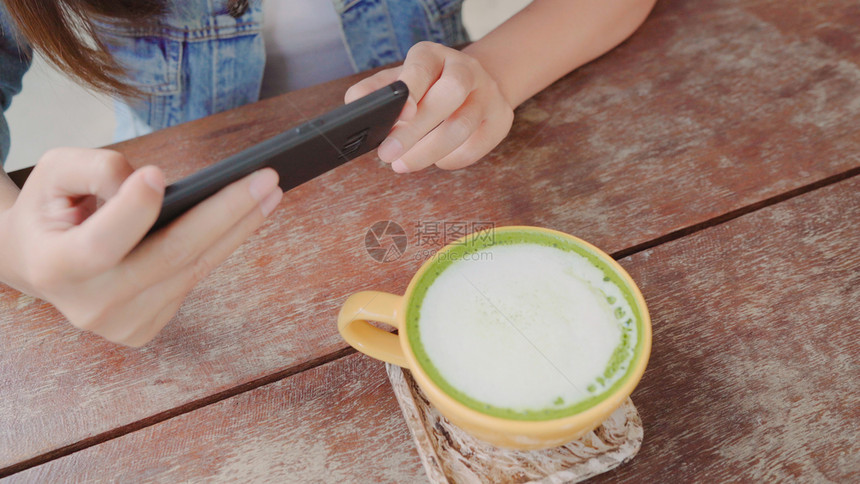 一位年轻女子在智能手机上拍摄咖啡茶图片