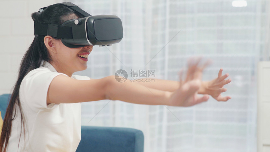 使用眼镜虚拟现实模器在客厅玩电子游戏的女青少年妇图片