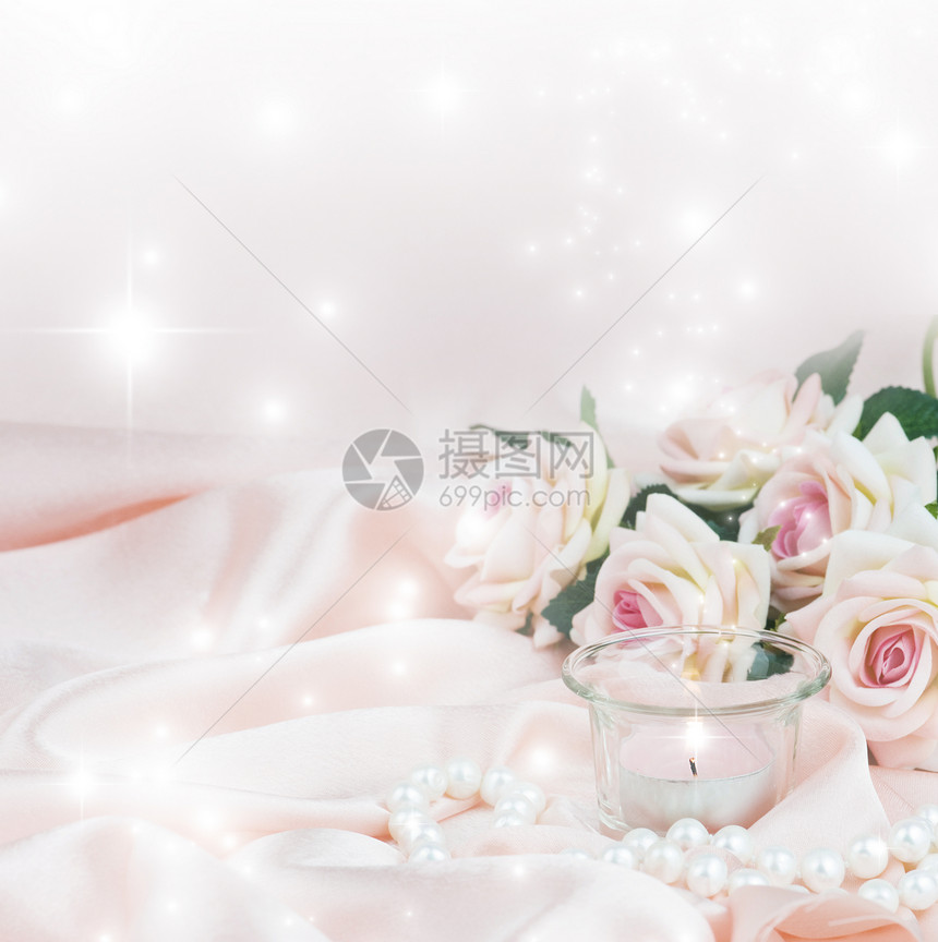 用粉红玫瑰烧蜡烛和丝织底上的珍珠项链图片