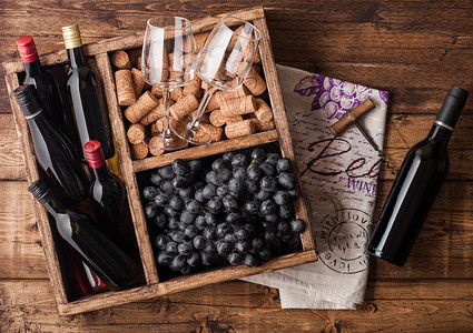 红酒小瓶子和杯空黑葡萄有软木塞和开瓶器装在旧木箱里放制本底图片