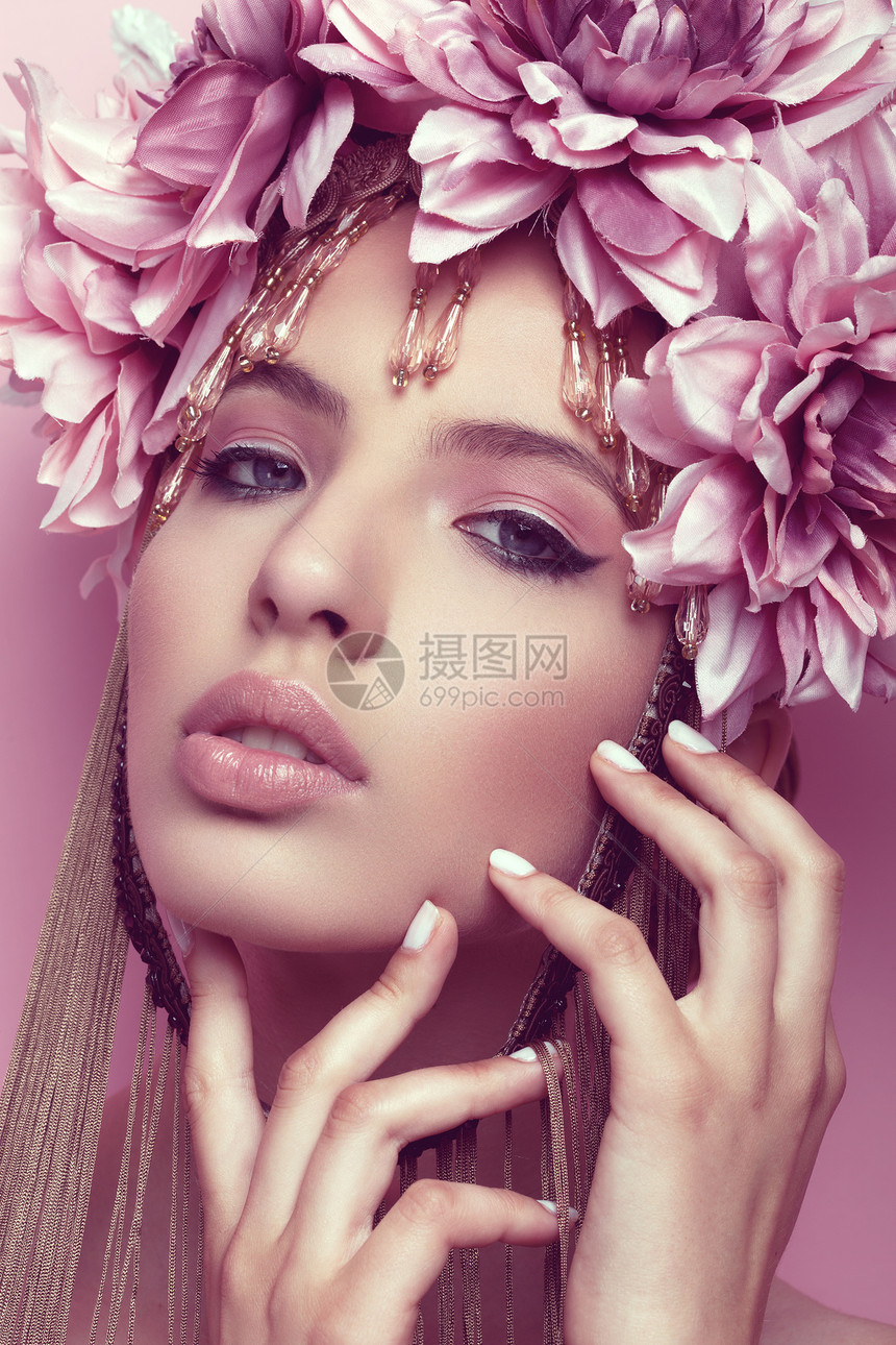 美丽的女士有花冠和粉红背景的化妆品手握在下巴图片