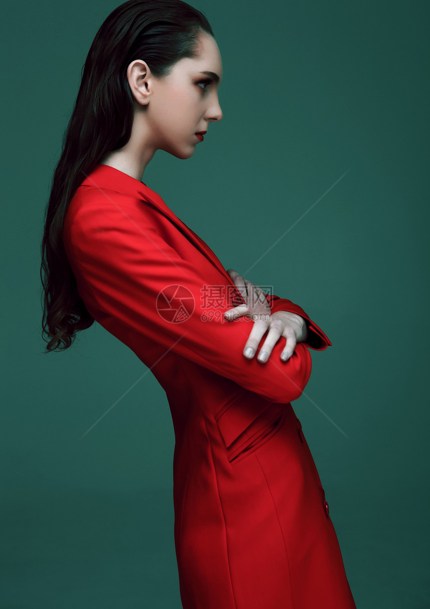 时装模特湿发穿绿色背景的红大衣时装肖像图片