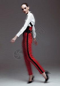 穿着红裤子和灰底白衬衫的漂亮时装模特背景图片