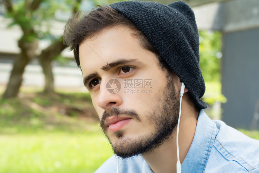 年轻人在阳光明媚的一天用耳机收听音乐的肖像图片