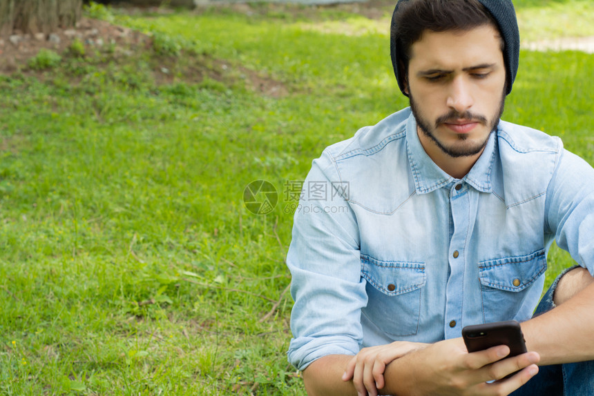 年轻拉丁男子使用智能手机的肖像户外图片