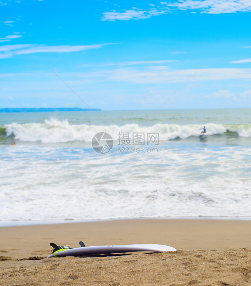 在沙滩上冲浪板者骑在背景的波浪上baliIndoesia图片