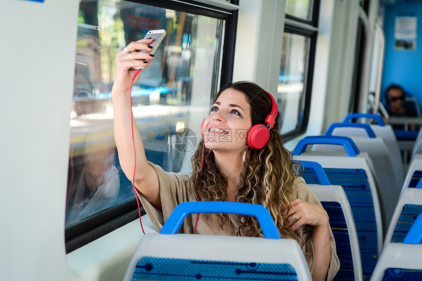 随身携带手机在火车上玩自拍的少女享受旅行图片