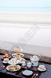夏季在海滩边的沙下午茶配有深色大理石桌上面包甜点和糕饼面包店甜点图片