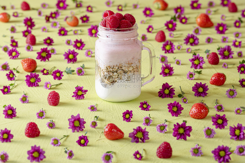 一份健康早餐混合食素和水果酸奶放在一个罐子里用粉红花装饰的绿色桌上图片